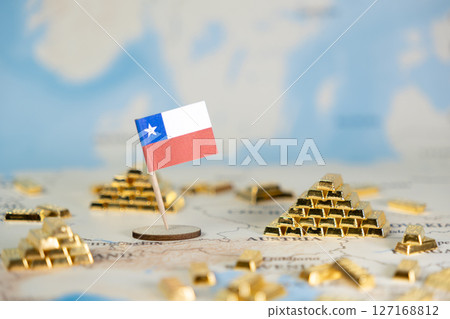 A small flag of Chile stands proudly amidst piles of shining gold bars on a world map, symbolizing the nation's rich natural resources and global economic significance 127168812
