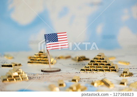 American flag miniature stands on a world map surrounded by stacked gold bars, symbolizing economic power, global investment, and national treasury 127168823