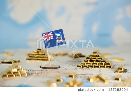 Falkland Islands flag stands prominently on a global map, surrounded by glistening gold bars, signifying national wealth, strategic resources, and economic investment potential 127168904