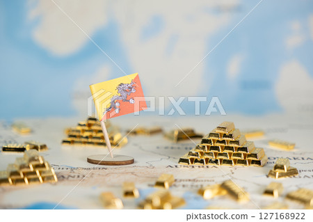 Bhutan flag and numerous gold bars symbolizing national wealth, global finance, and economic growth on a world map with ample copy space 127168922
