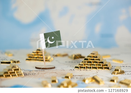 Miniature Pakistan flag and gold bars on a world map symbolize national wealth, economic growth, and global finance, offering ample copy space 127168929