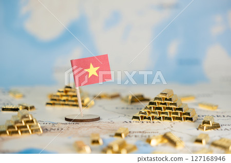 A miniature Vietnamese flag stands prominently on a detailed world map, surrounded by gleaming gold bar stacks, symbolizing national economic wealth and global investment strategy concepts 127168946