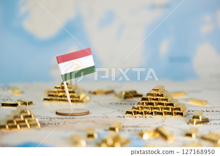 Tajikistan flag and gold bars displayed on a world map, symbolizing national wealth, economic growth, and global financial markets with ample copy space 127168950