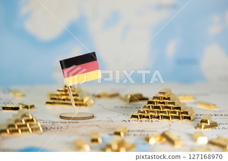 German flag prominently on a global map, surrounded by shining gold bars, symbolizing nation's economic power, wealth, and strategic investment 127168970