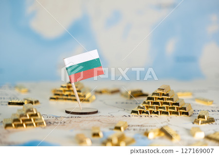 A Bulgarian flag stands prominently on a global map, surrounded by numerous gold bars, symbolizing national wealth, economic prosperity, and financial stability with central copy space 127169007