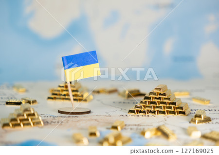 Ukrainian flag with mini gold bars on a detailed map represents national wealth, economic resilience, and strategic resource control amidst global challenges 127169025