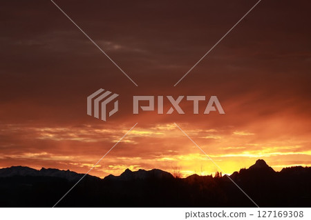 The sky is orange and the mountains are in the background The sky is orange and the mountains are in the background 127169308