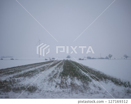 Snowy field with a windmill in the background Snowy field with a windmill in the background 127169312