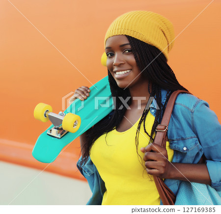 Summer portrait of stylish happy African young woman with skateboard, modern black teenage girl Summer portrait of stylish happy African young woman with skateboard, modern black teenage girl 127169385