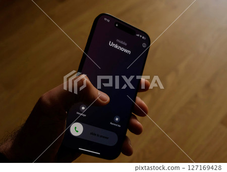 Fraud or fraudulent schemes. Close-up of a male hand holding a phone with an unexpected incoming call from an unknown Fraud or fraudulent schemes. Close-up of a male hand holding a phone with an unexpected incoming call from an unknown 127169428