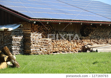A large pile of wood stacked against a building 127169783