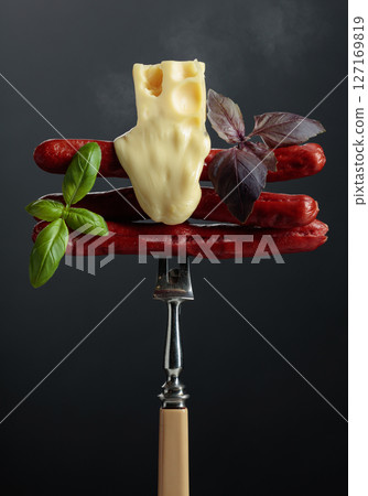 Grilled thin sausages with cheese and basil. 127169819