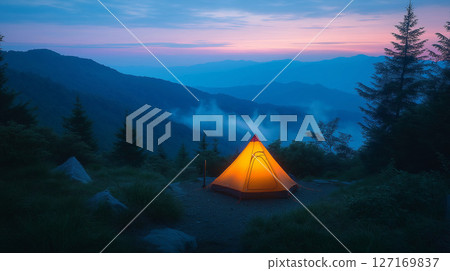 籠罩在紫色暮色中的山區和一頂亮著燈的單人露營帳篷 127169837