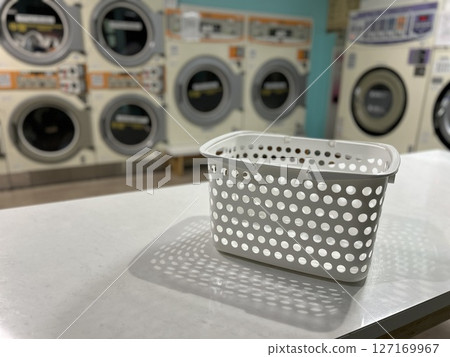 Coin laundry: Dryers lined up behind laundry baskets 127169967