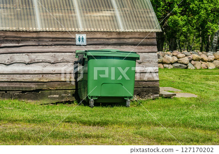 Green waste bin by rustic wooden building with unisex toilet sign on wall. High quality photo Green waste bin by rustic wooden building with unisex toilet sign on wall. High quality photo 127170202