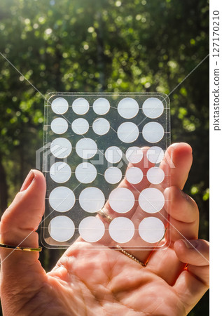 Hand holding transparent acne patch sheet with round stickers in natural sunlight. High quality photo Hand holding transparent acne patch sheet with round stickers in natural sunlight. High quality photo 127170210