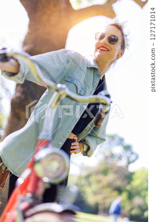 Portrait young adult pretty woman with red vintage retro bike and pin-up casual outfit green city park bright sunny summer day. Happy beautiful female person cycling outdoors. Healthy lifestyle Portrait young adult pretty woman with red vintage retro bike and pin-up casual outfit green city park bright sunny summer day. Happy beautiful female person cycling outdoors. Healthy lifestyle 127171014