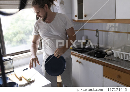 Man preparing ingredients and picking up plate in kitchen 127171443