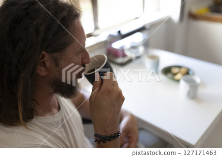 Man drinking coffee in kitchen during morning routine 127171463
