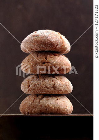 Stack of baked ginger snap cookies with crispy crust on dark rustic wooden background close up 127171522
