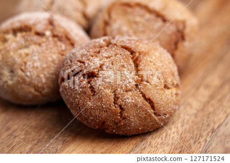 Homemade vegan gingersnap cookies on wooden table close up with crispy cracked crust texture Homemade vegan gingersnap cookies on wooden table close up with crispy cracked crust texture 127171524