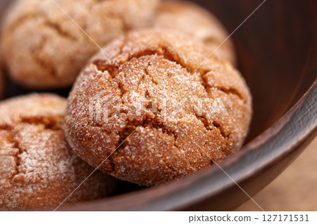 Ginger snap cookies in wooden bowl. Crumbly crispy baked snack with cracked texture. Macro. Ginger snap cookies in wooden bowl. Crumbly crispy baked snack with cracked texture. Macro. 127171531