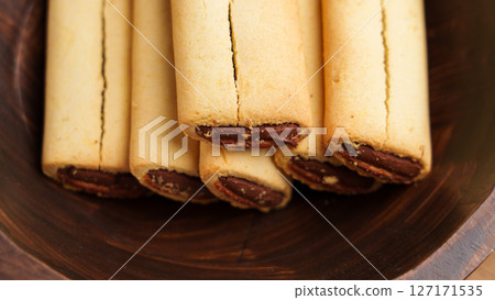 Fig filled bar cookies in rustic wooden bowl. Traditional sweet pastry. Top view.  127171535