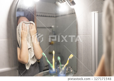Woman drying face with towel after hot shower in bathroom 127171548