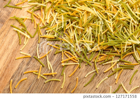Colored angel hair vermicelli on rustic wooden surface. Italian uncooked pasta. Top view Colored angel hair vermicelli on rustic wooden surface. Italian uncooked pasta. Top view 127171558