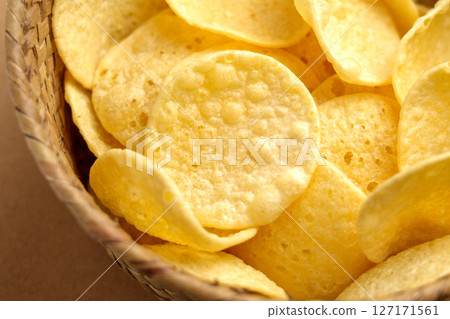 Crispy potato chips in rustic wicker bowl. Junk food snack. Close-up Crispy potato chips in rustic wicker bowl. Junk food snack. Close-up 127171561