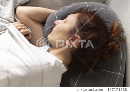 Woman sleeping peacefully in bed on gray pillow 127171588
