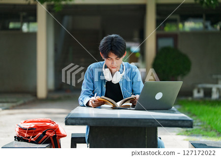 College student studying on campus outdoor with laptop casual lifestyle. College student studying on campus outdoor with laptop casual lifestyle. 127172022