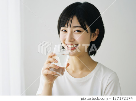 Portrait of a healthy and clean-looking woman drinking water with a smile (AI-generated image) 127172174