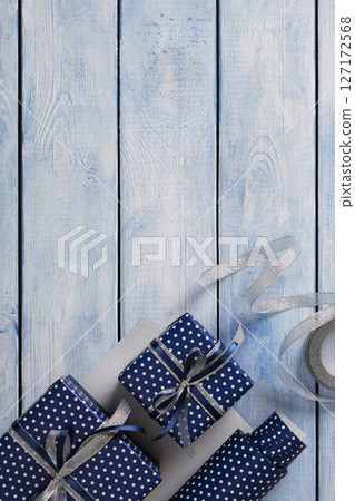 Gift wrapping items. Rolls of wrapping paper, scissors, ribbon, ready-wrapped gifts. Blue wooden background, space for your text. Gift wrapping items. Rolls of wrapping paper, scissors, ribbon, ready-wrapped gifts. Blue wooden background, space for your text. 127172568