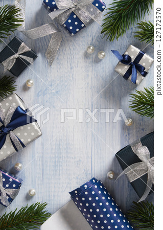 A frame made of fir branches, gift boxes, ribbons, and wrapping paper in blue and silver colors. Space for your text. 127172570