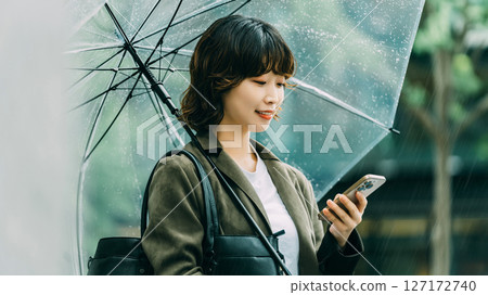 一名女子在傘下使用智慧型手機(雨季,六月) 一名女子在傘下使用智慧型手機(雨季,六月) 127172740
