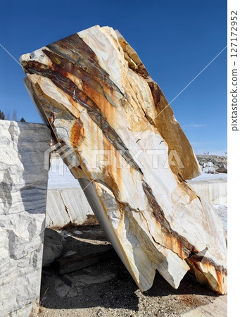 large striking piece marble showcasing natural patterns in quarry under bright blue sky. closeup. large striking piece marble showcasing natural patterns in quarry under bright blue sky. closeup. 127172952