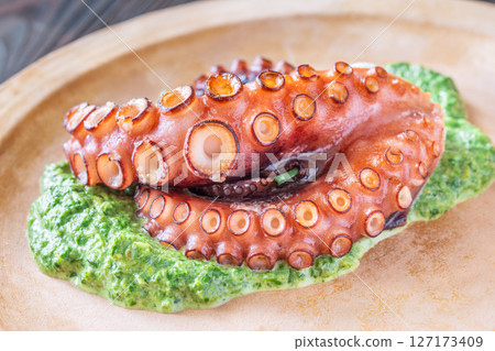 Baked Octopus Tentacles With Creamed Spinach Served On A Rustic Plate 127173409