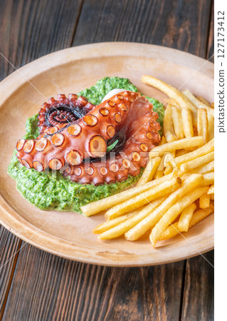 Baked Octopus With Creamy Spinach And Fries On A Rustic Plate Baked Octopus With Creamy Spinach And Fries On A Rustic Plate 127173412