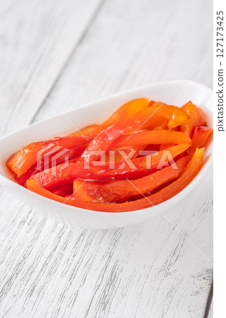 Grilled red bell pepper slices placed in clean white ceramic serving bowl 127173425