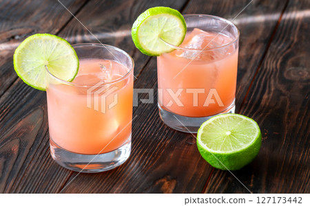 Two guava margaritas with lime wheels glow against rich dark cocktail backdrop Two guava margaritas with lime wheels glow against rich dark cocktail backdrop 127173442