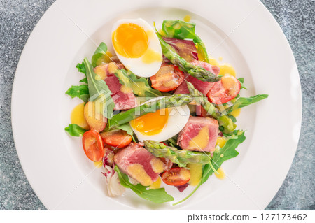Elegant Nicoise portion with eggs, tuna, arugula, asparagus, cherry tomatoes, white plate Elegant Nicoise portion with eggs, tuna, arugula, asparagus, cherry tomatoes, white plate 127173462