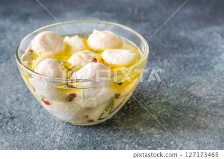 Glass bowl of labneh balls in oil, spiced with garlic and rosemary Glass bowl of labneh balls in oil, spiced with garlic and rosemary 127173465