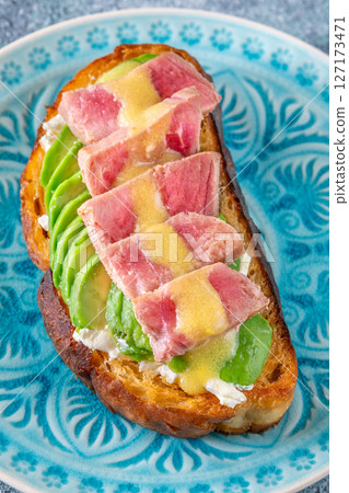 Tuna avocado sandwich with labneh and mustard-lemon sauce on toasted bread 127173471