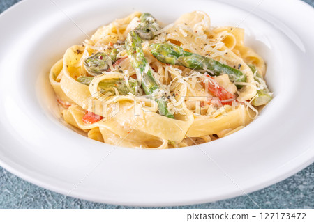 Tagliatelle pasta with creamy garlic sauce, asparagus, peppers, and parmesan topping Tagliatelle pasta with creamy garlic sauce, asparagus, peppers, and parmesan topping 127173472