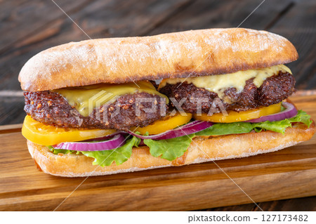 Hearty Ciabatta Sandwich Stacked With Beef Patties, Yellow Tomatoes, And Crisp Lettuce 127173482