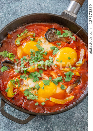 Shakshuka with mushrooms and yellow peppers topped with eggs and cilantro 127173829