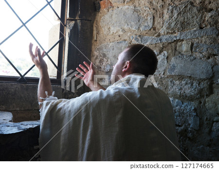 Ancient man praying at the window Ancient man praying at the window 127174665