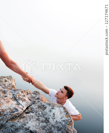 Man help his friend to climb on the rock Man help his friend to climb on the rock 127174671