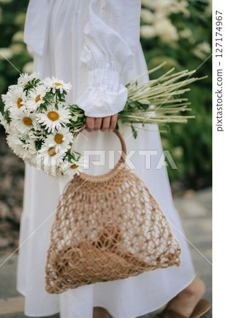 Woman Holding Daisies and a Woven Bag 127174967